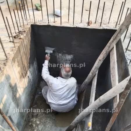 Worker Applying Waterproofing Material Inside a Basement Pit in Pakistan